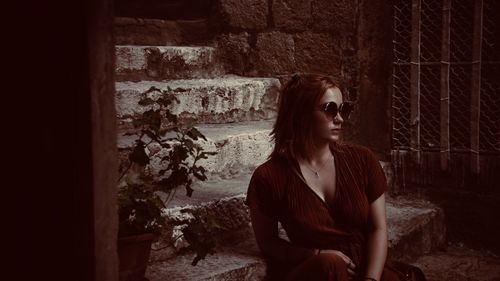 Woman looking away while sitting on wall