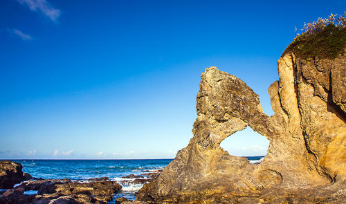 Rock formation in sea against blue sky