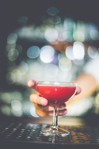 Close-up of hand holding cocktail glass on table