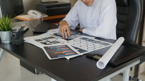 Midsection of businessman using laptop at office