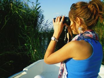 Side view of woman looking through binoculars