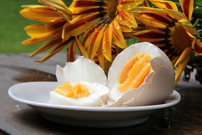 Close-up of cracked boiled egg by flowers on table