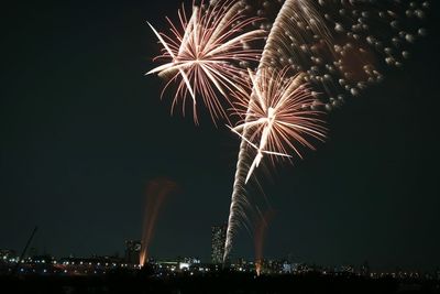 Low angle view of firework display over city at night