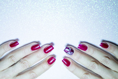 Close-up of woman with pink nail polish on shiny table