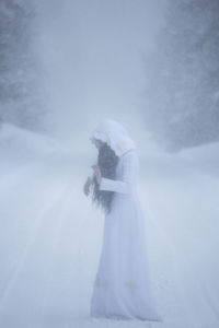 Side view of woman standing in snow