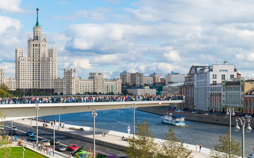 City by river and buildings against sky