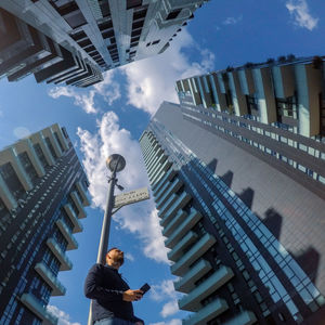 Low angle view of person standing by buildings against sky