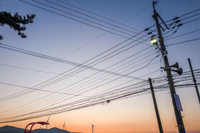 Low angle view of silhouette electricity pylon against sky during sunset