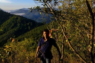 A male traveler exploring top of mountain on foggy morning, trekking in forest on vacations trip