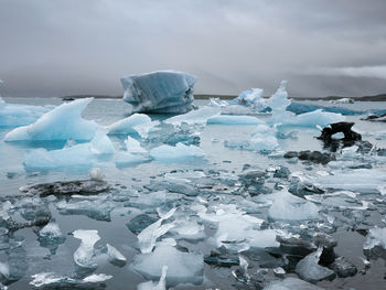 Ice floating on water against sky during winter