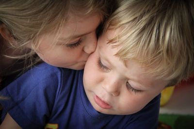 Close-up of sister kissing brother at home