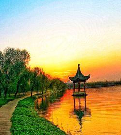 Gazebo in lake against clear sky at sunset