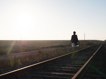 Rear view of woman walking on railroad track