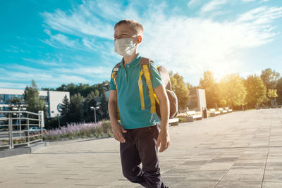 Portrait of young man standing on footpath