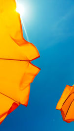 Low angle view of parasols against clear sky during sunny day