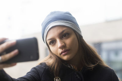 Young woman with cap outside taking a selfie