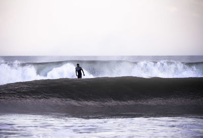 Man surfing in sea against sky