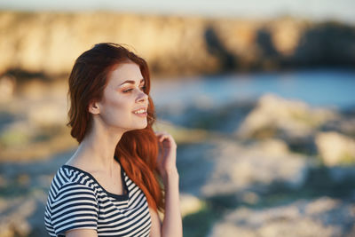 Young woman looking away while standing at shore
