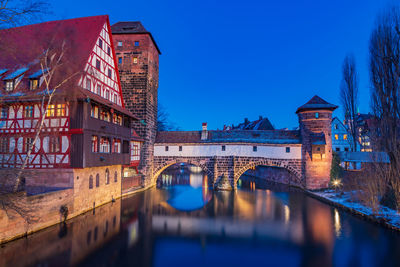 Reflection of illuminated bridge over river in city