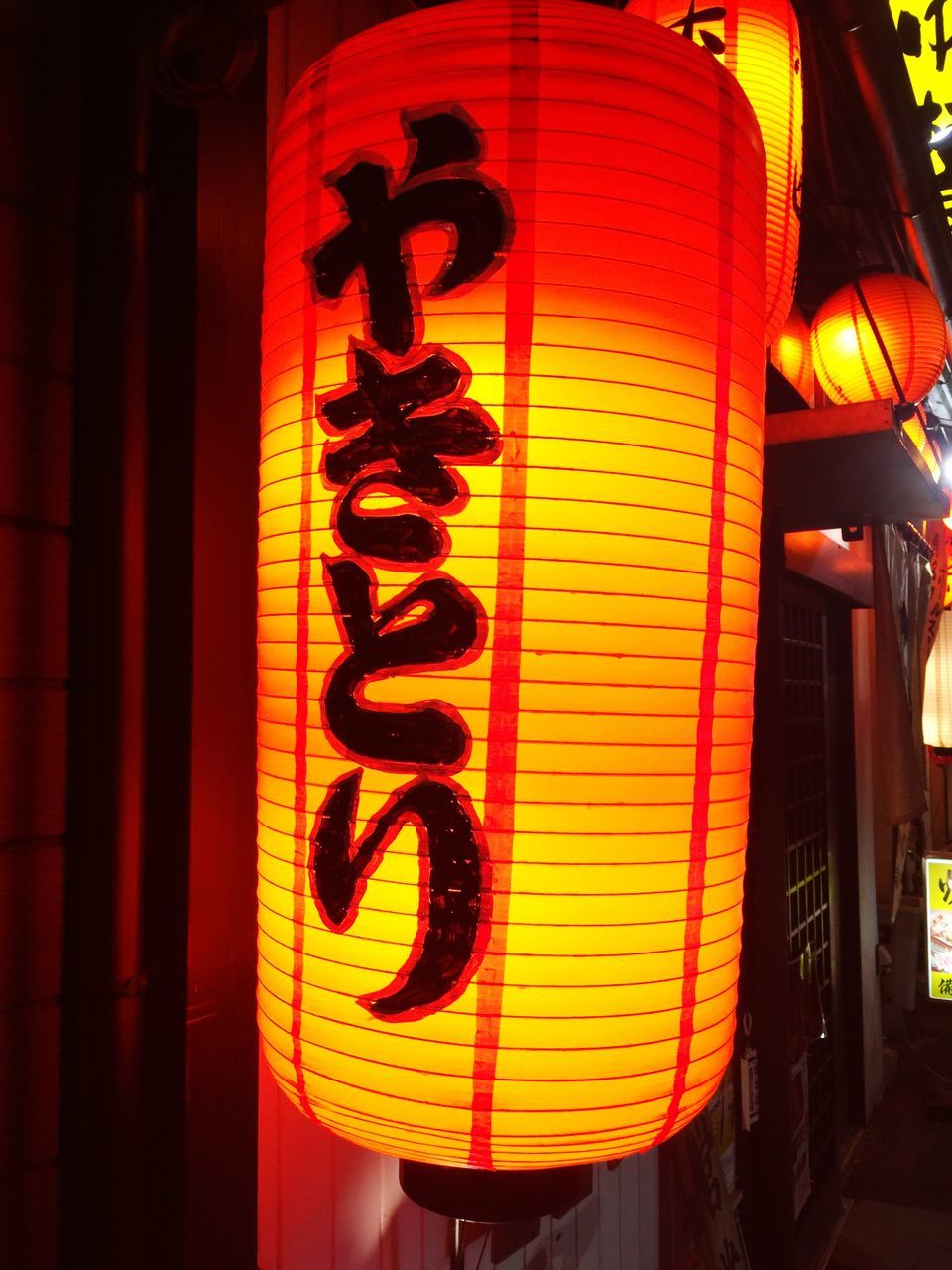 hanging, yellow, lantern, orange color, illuminated, low angle view, built structure, lighting equipment, building exterior, creativity, red, art and craft, art, outdoors, wall - building feature, architecture, protection, safety, sunlight, night