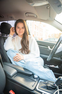 Portrait of young woman sitting in car