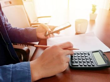 Midsection of person using mobile phone at table