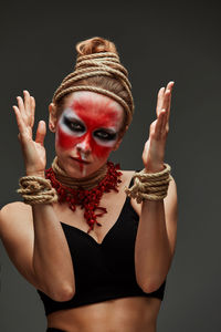 Young woman with arms raised against black background