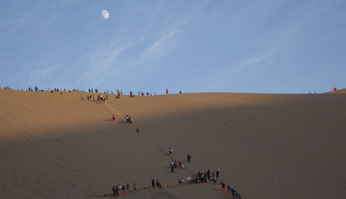 People on sand dune against sky