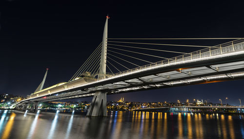 Illuminated bridge over river at night