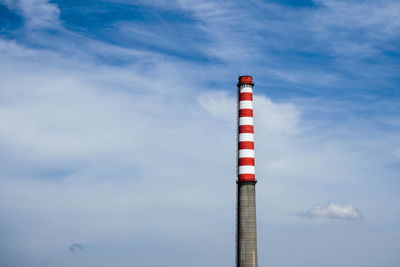 Low angle view of smoke stack against cloudy sky