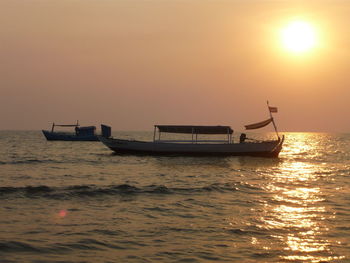 Boat sailing in sea at sunset