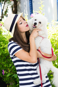 Young woman with dog against plants