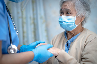 Midsection of doctor holding patient hand in hospital