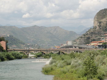 Bridge over river by mountains against sky
