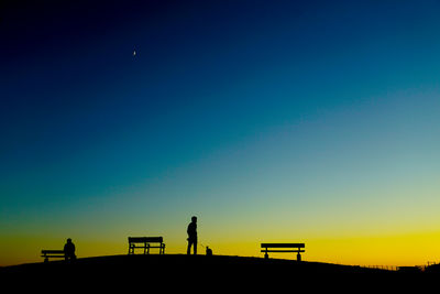 Low angle view of man standing against clear sky during sunset