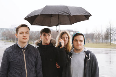 Friends with umbrella standing in city during rainy season