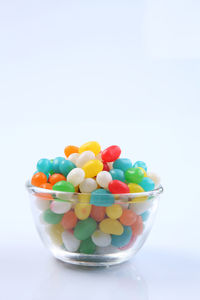 Multi colored candies in bowl against white background