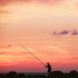 Silhouette of woman standing on landscape at sunset