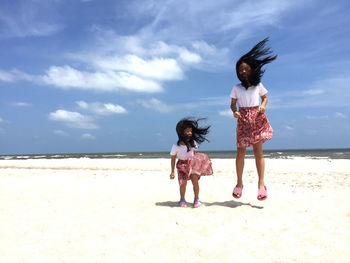 Rear view of women on beach against sky