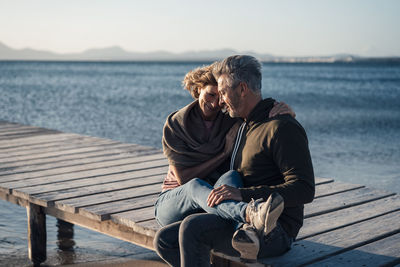 Happy mature couple sitting on jetty