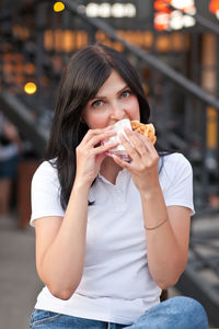 Portrait of young woman eating ice cream in city