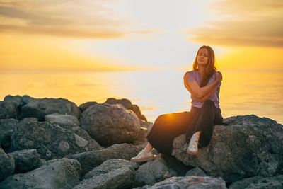 Young woman sitting on rock at beach