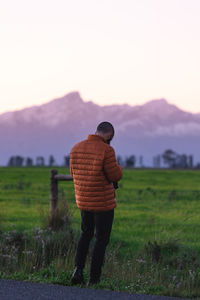 Rear view of man standing on field against sky