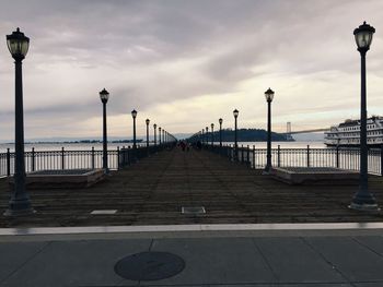 Pier on sea against cloudy sky