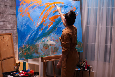 Rear view of woman painting at home