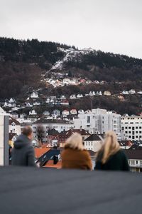 People in city by buildings against sky