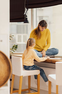 Side view of young woman sitting at home