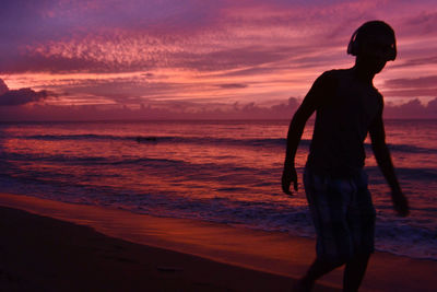 Silhouette of people on beach at sunset