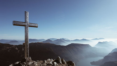 Cross on mountains against sky