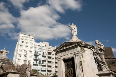 Low angle view of statue against building against sky